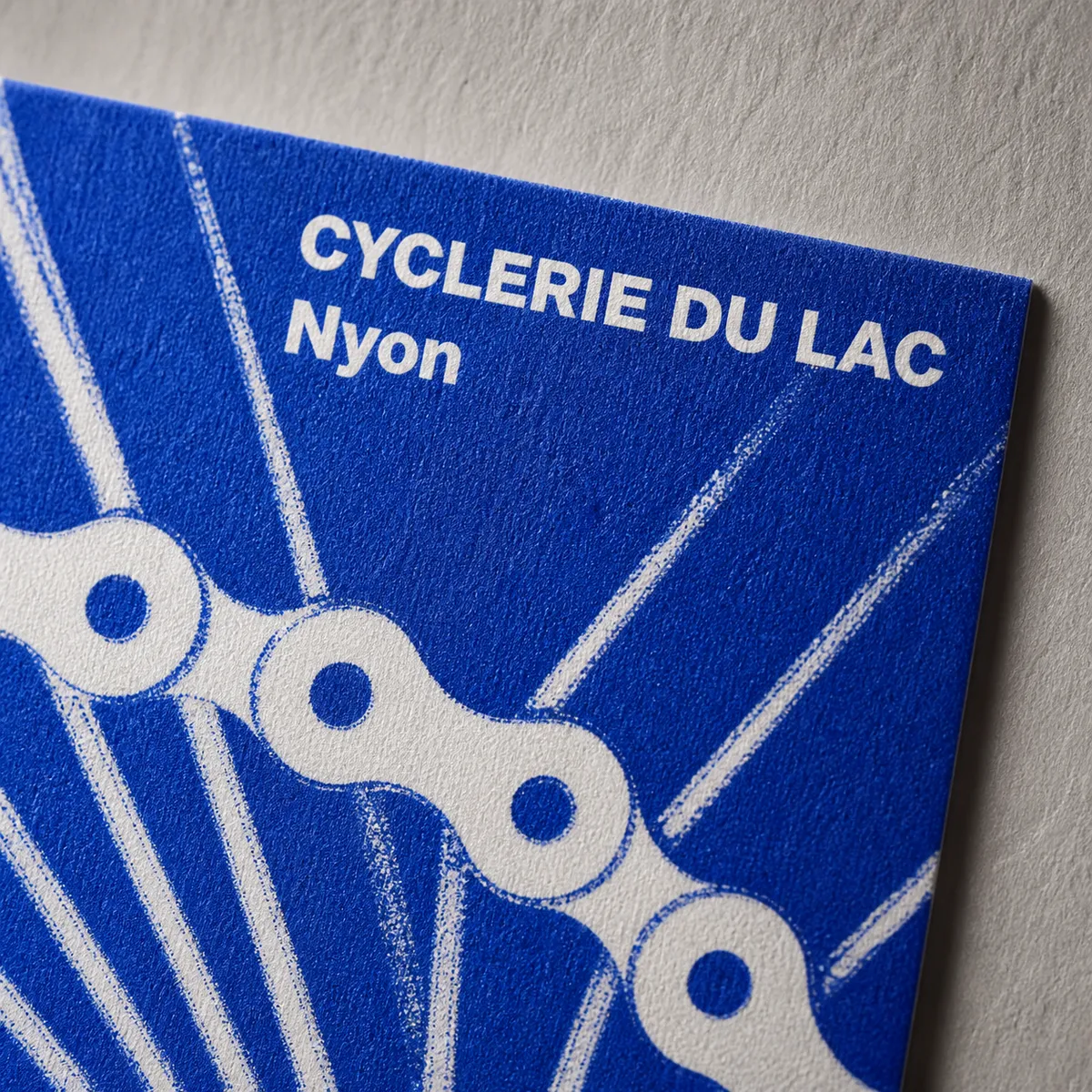 Gros plan macro sur le coin d'une carte de visite bleu électrique et blanc en duotone - vélociste fictif Cyclerie du Lac - carte de visite